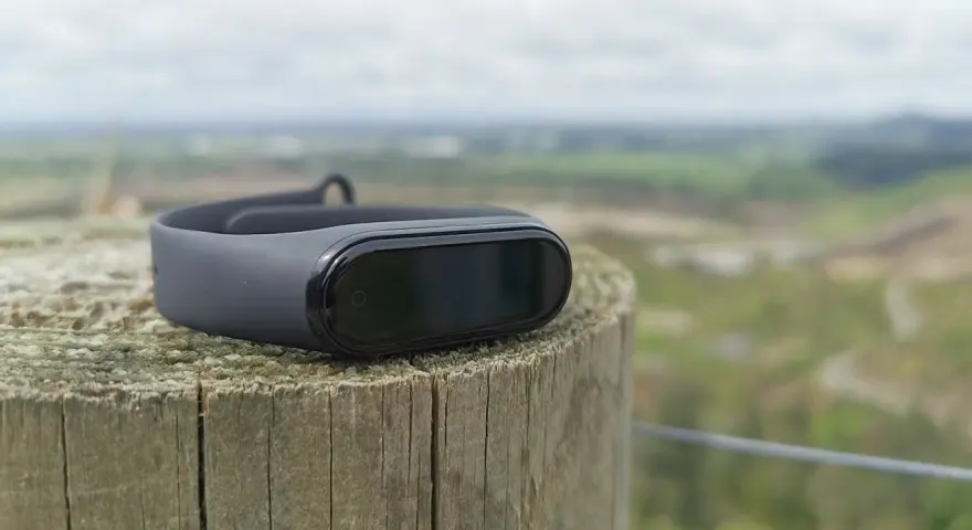 Czarny Mi Band 4 na drewnianym słupku, idealny do śledzenia aktywności. To najlepsza aplikacja do Mi Band 4 dla aktywnych osób.
