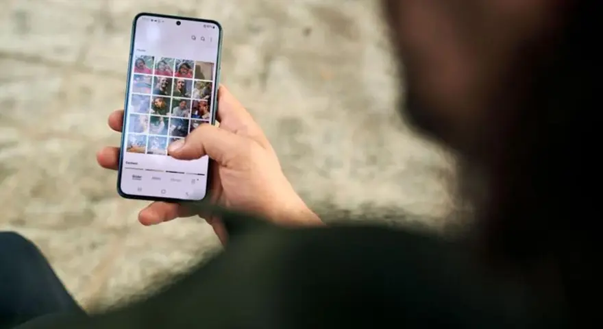 Osoba przegląda zdjęcia na telefonie, zastanawiając się, jak usunąć aplikacje z telefonu, by zwolnić miejsce.
