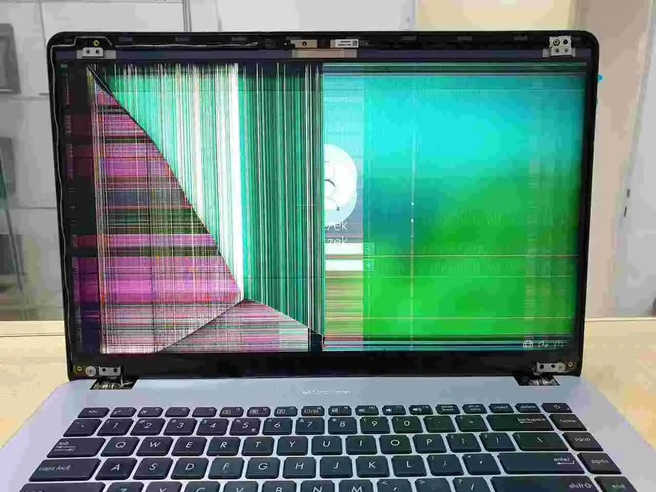 Uszkodzona matryca w laptopie wyświetla kolorowe pasy i zakł&oacute;cenia, uniemożliwiając normalne użytkowanie.