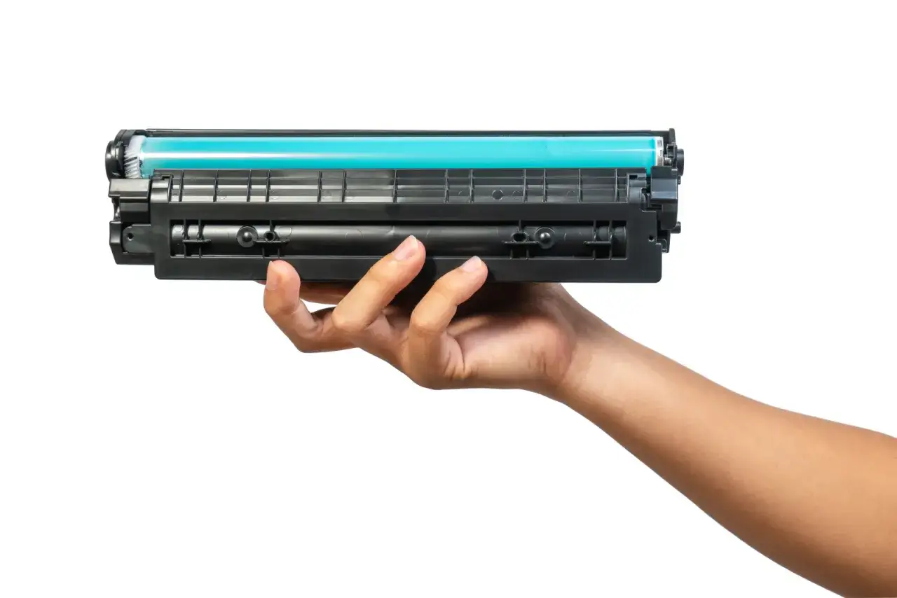 Dłoń trzyma toner do drukarki HP. Dowiedz się, jak wymienić tusz w drukarce HP, aby drukować bez problem&oacute;w.
